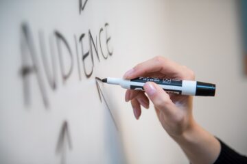 female hand writing on whiteboard with black marker