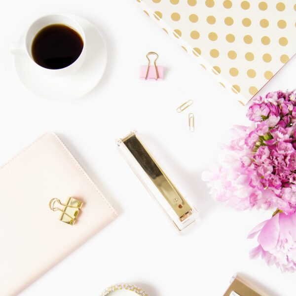 flat lay of pink desk accessories with a cup of coffee and pink flowers